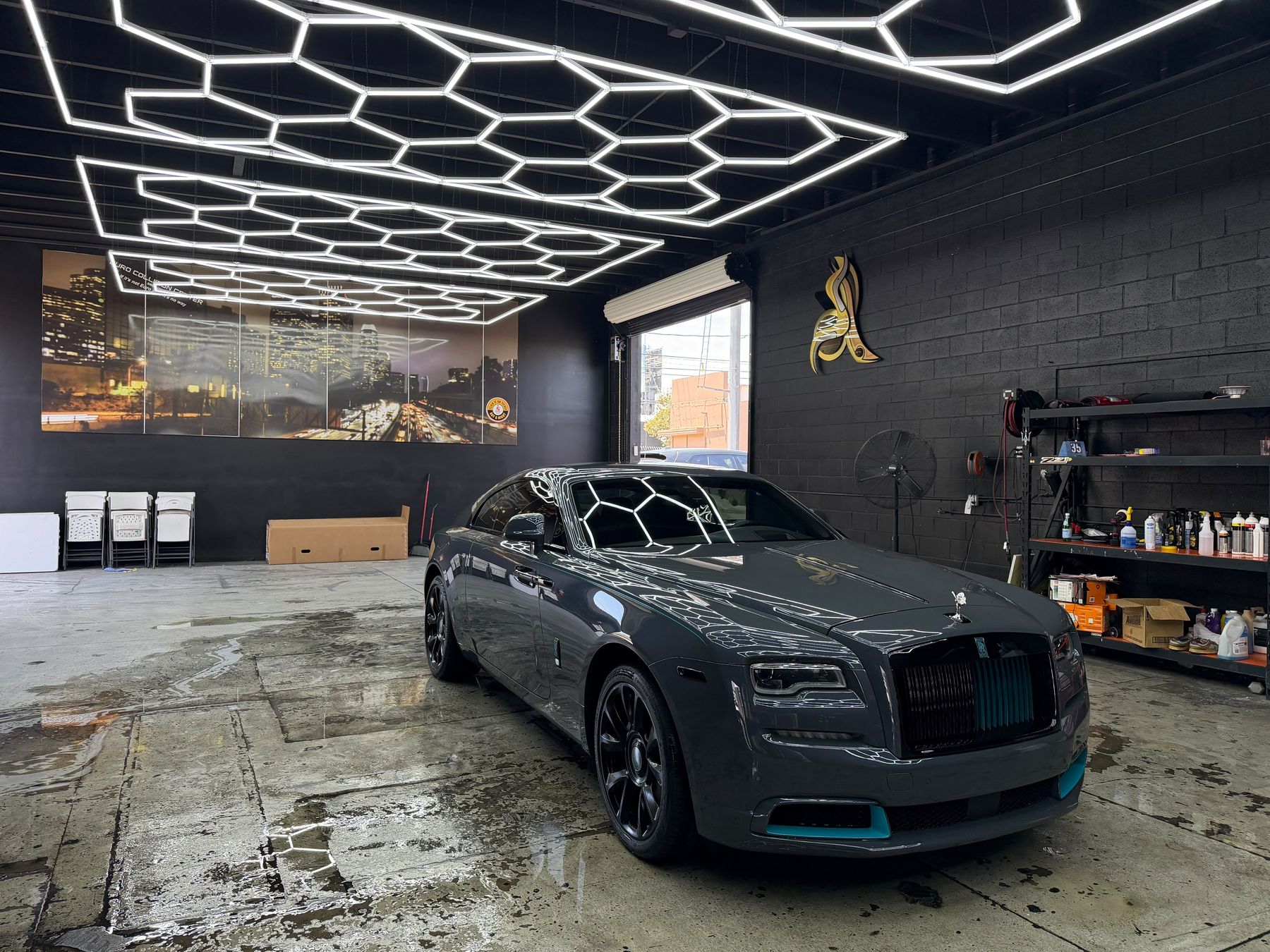 A Rolls-Royce Wraith in a detailing bay, hexagonal lights reflecting off freshly sealed paint